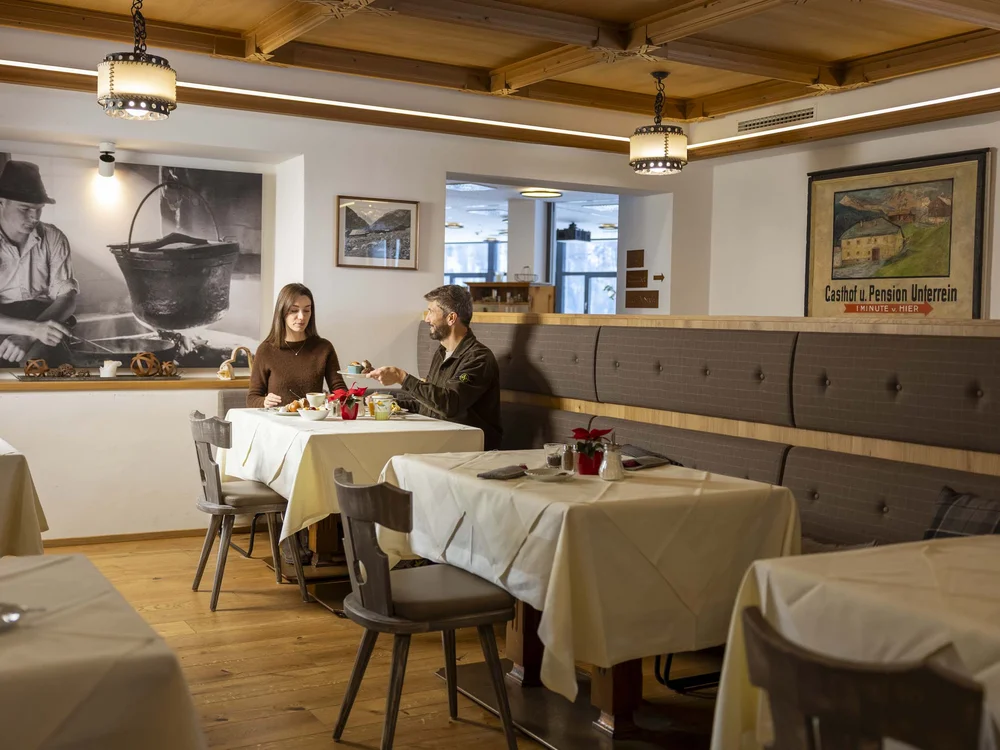 Due persone che mangiano in un ristorante con arredamento in legno e quadri alle pareti