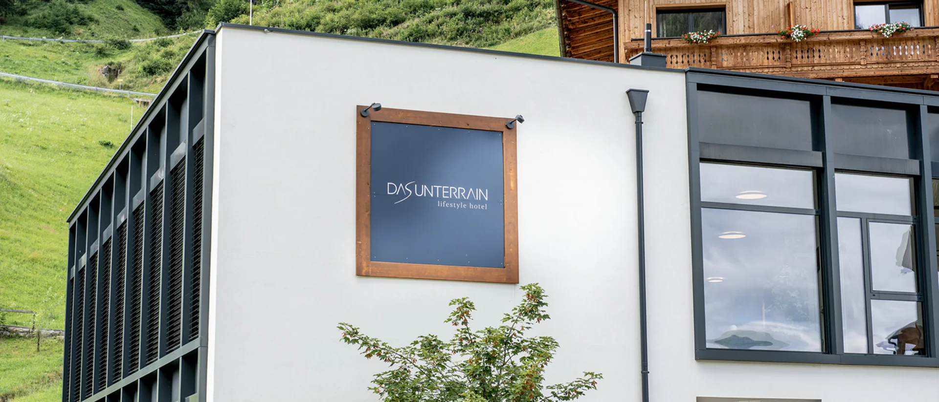 Facciata moderna dell'hotel lifestyle Das Unterrain con paesaggio montano verde