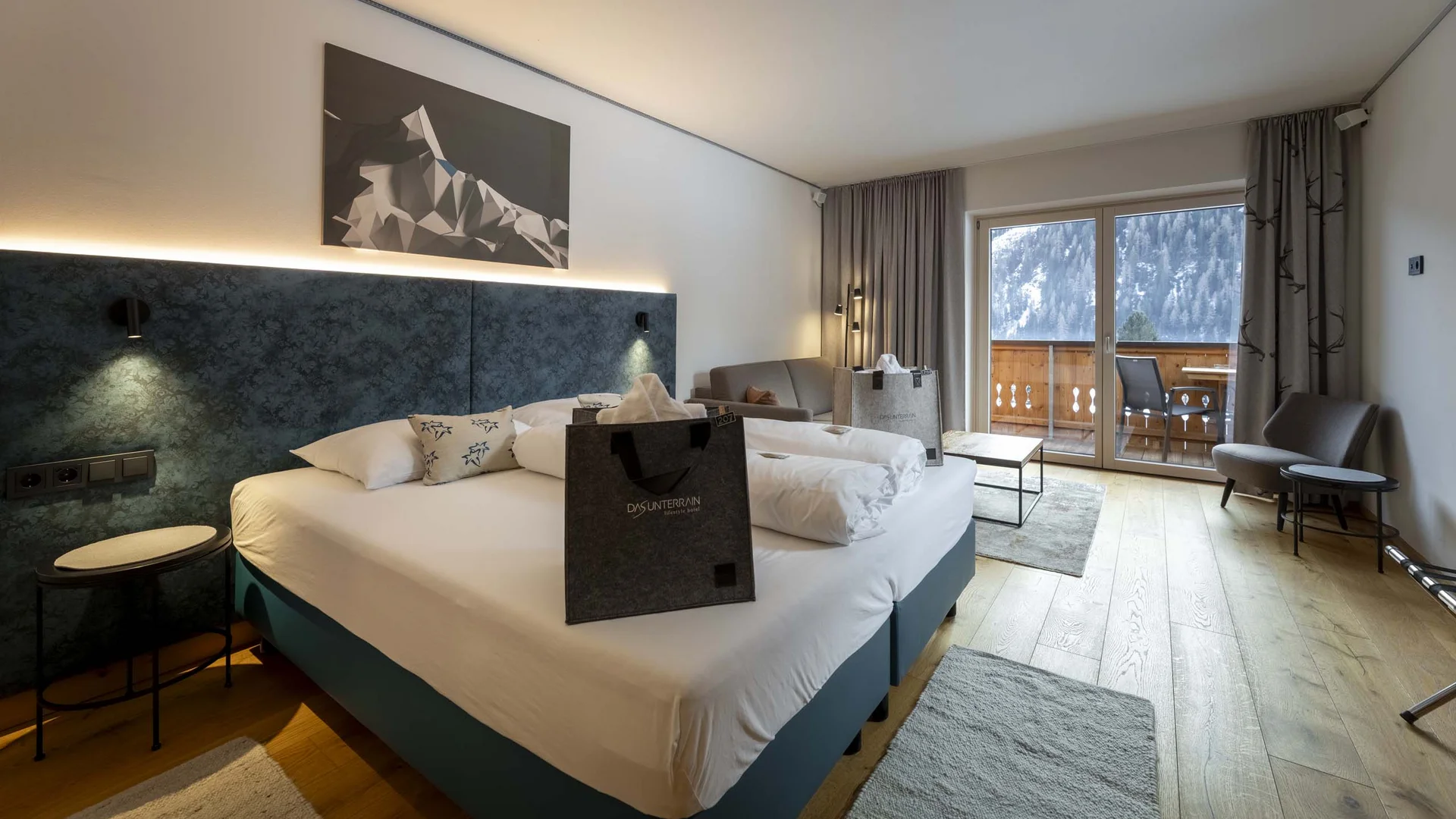 Camera d'albergo moderna con letto matrimoniale e balcone con vista sulla montagna