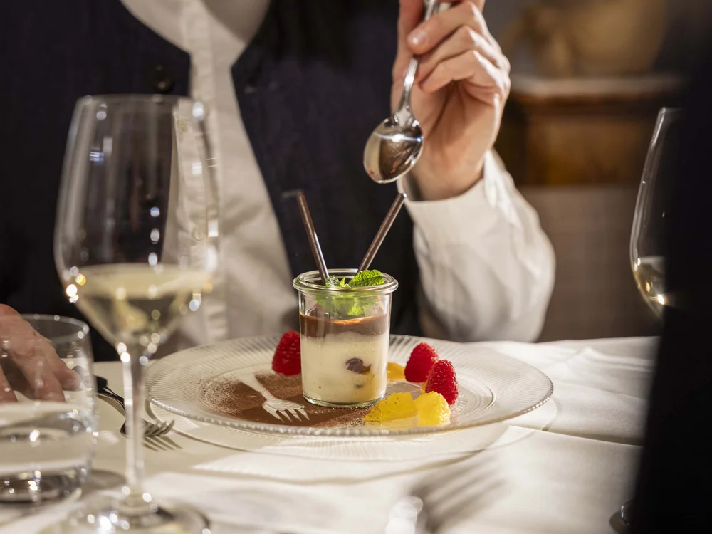 Dessert in bicchiere con frutti rossi e foglie di menta su piatto decorato