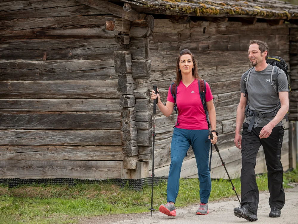 Coppia che fa trekking vicino a una casa di legno rustica