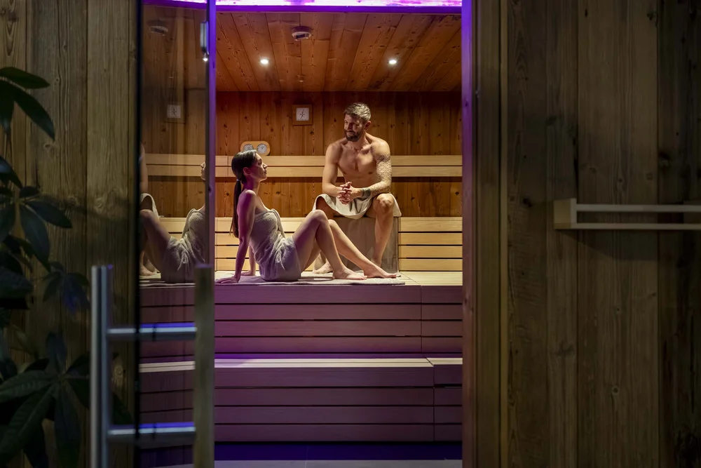 Coppia rilassata nella sauna con pareti in legno e illuminazione soffusa