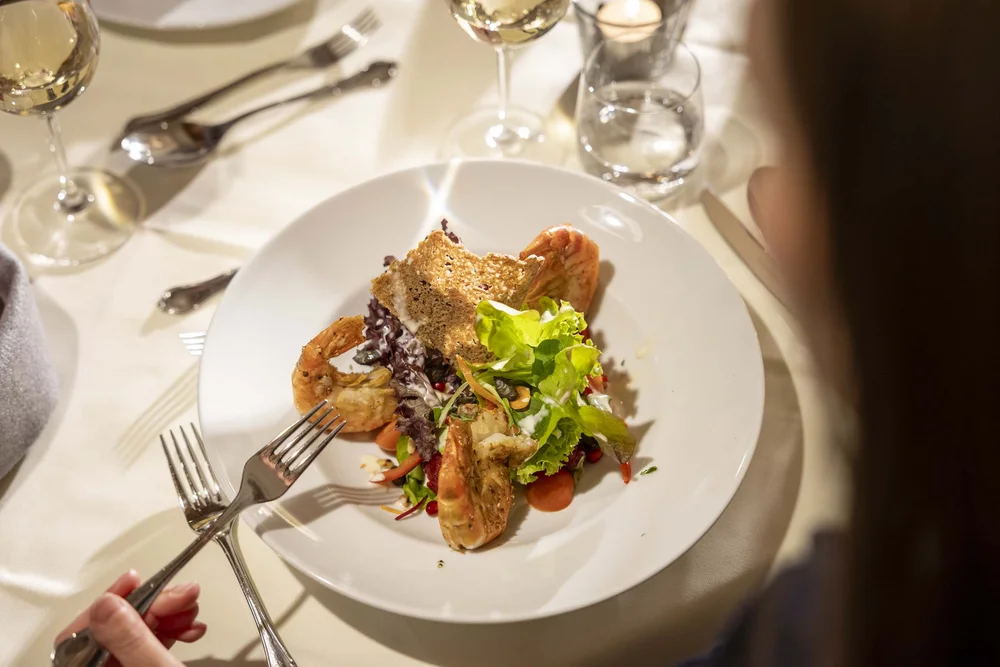 Insalata gourmet con gamberi, lattuga e crostini su piatto bianco