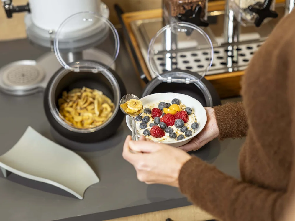 Persona che prende cereali con frutta fresca in una ciotola