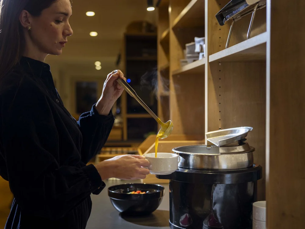 Donna che versa zuppa calda in una tazza in cucina
