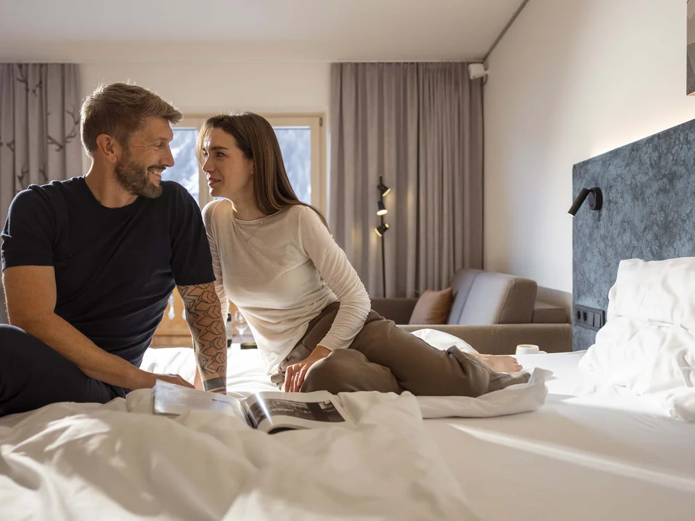 Coppia sorridente seduta sul letto in una stanza moderna