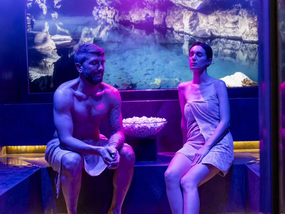 Due persone rilassate in una sauna con luci blu e viola