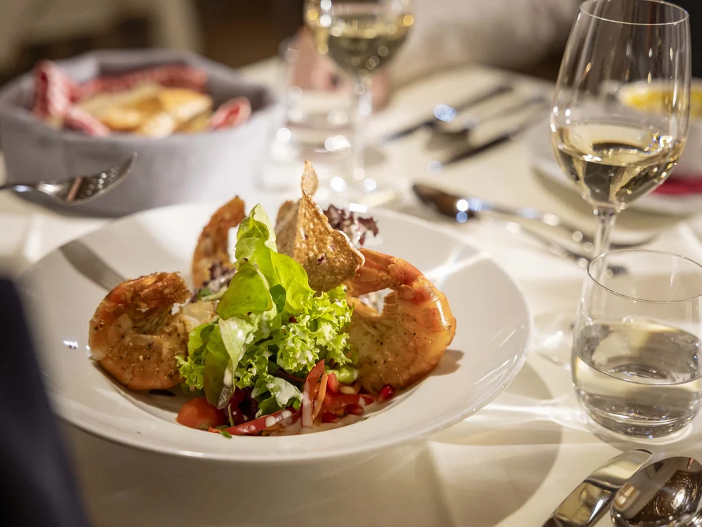 Insalata con gamberi e vino bianco su tavola elegante