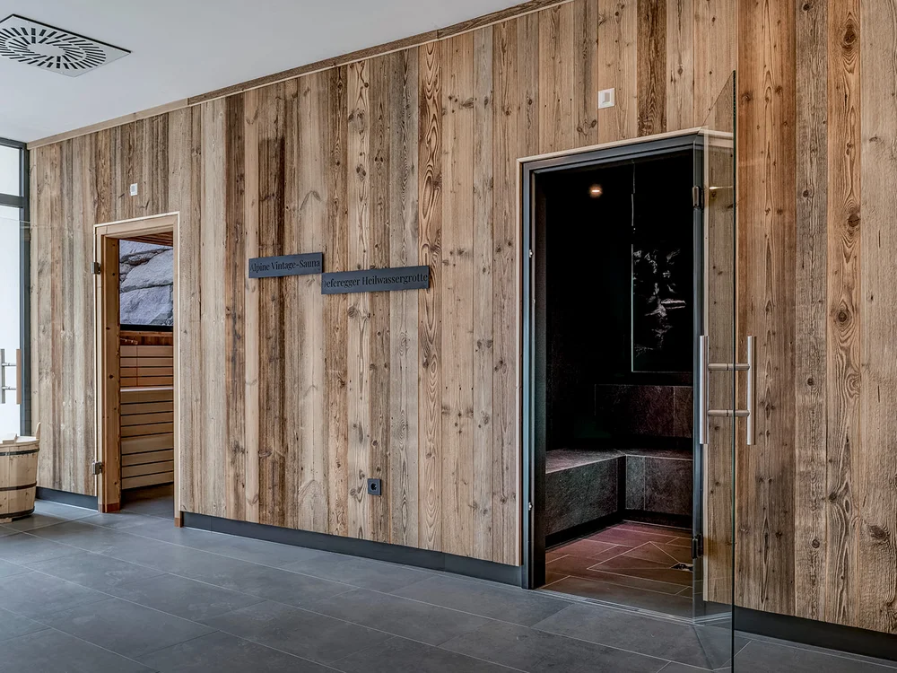 Parete in legno con ingresso a sauna e porta in vetro aperta