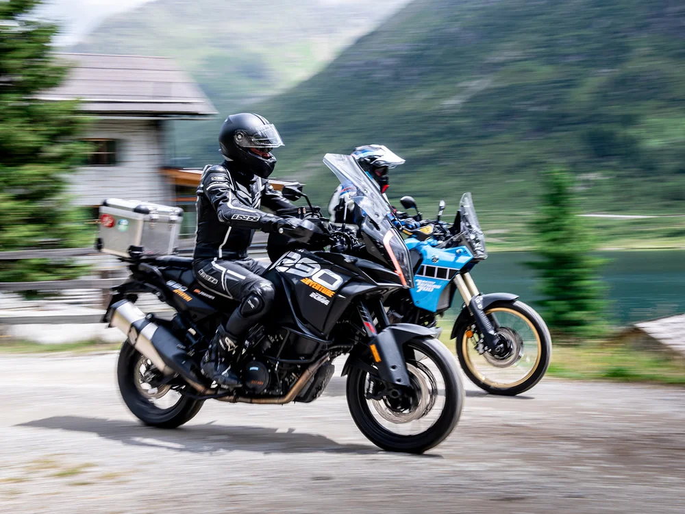 Due motociclisti con casco che guidano moto in montagna