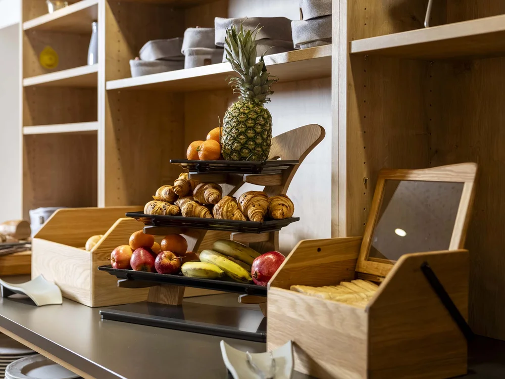 Frutta e croissant disposti su mensole in legno in un buffet
