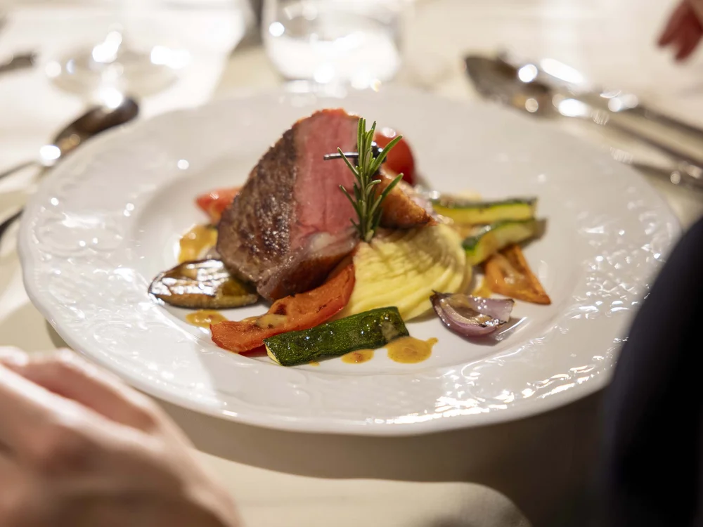 Piatto di carne con verdure grigliate e purè su tavola elegante