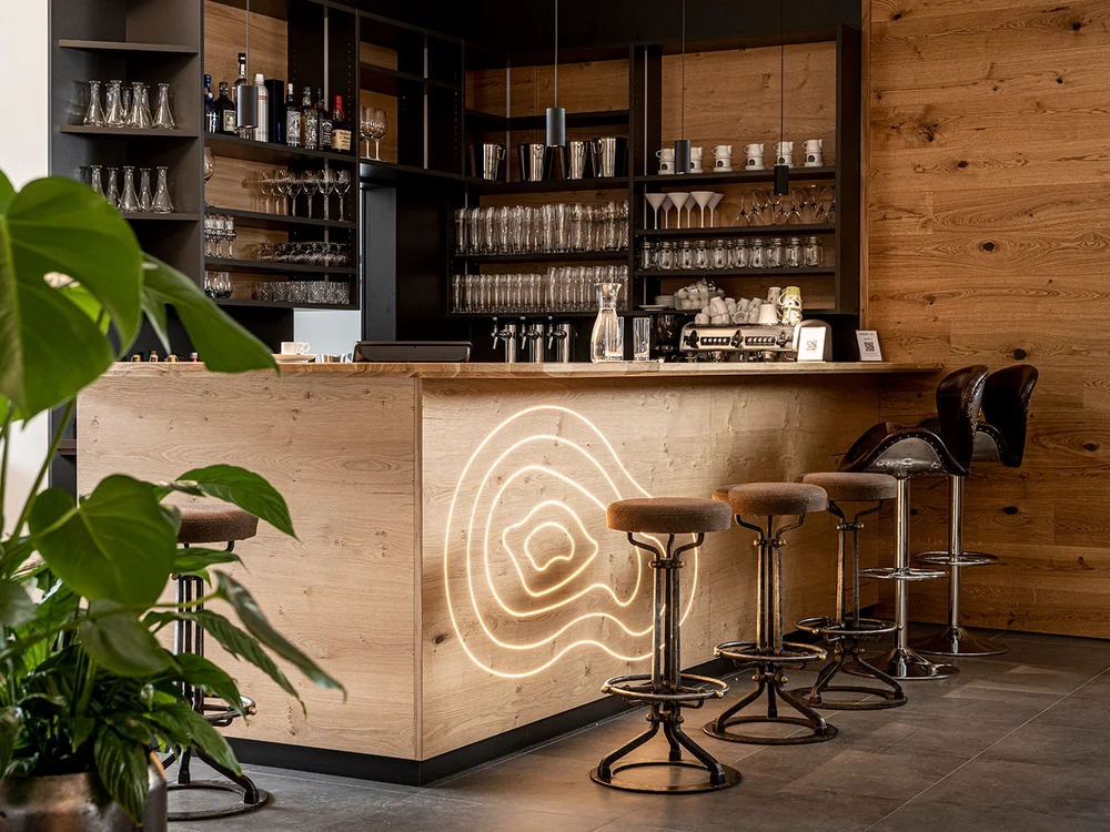 Bancone bar moderno in legno con sgabelli e scaffali per bicchieri