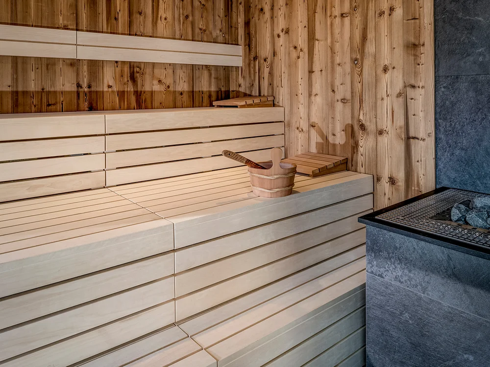 Interno di una sauna con panche in legno chiaro e secchio con mestolo