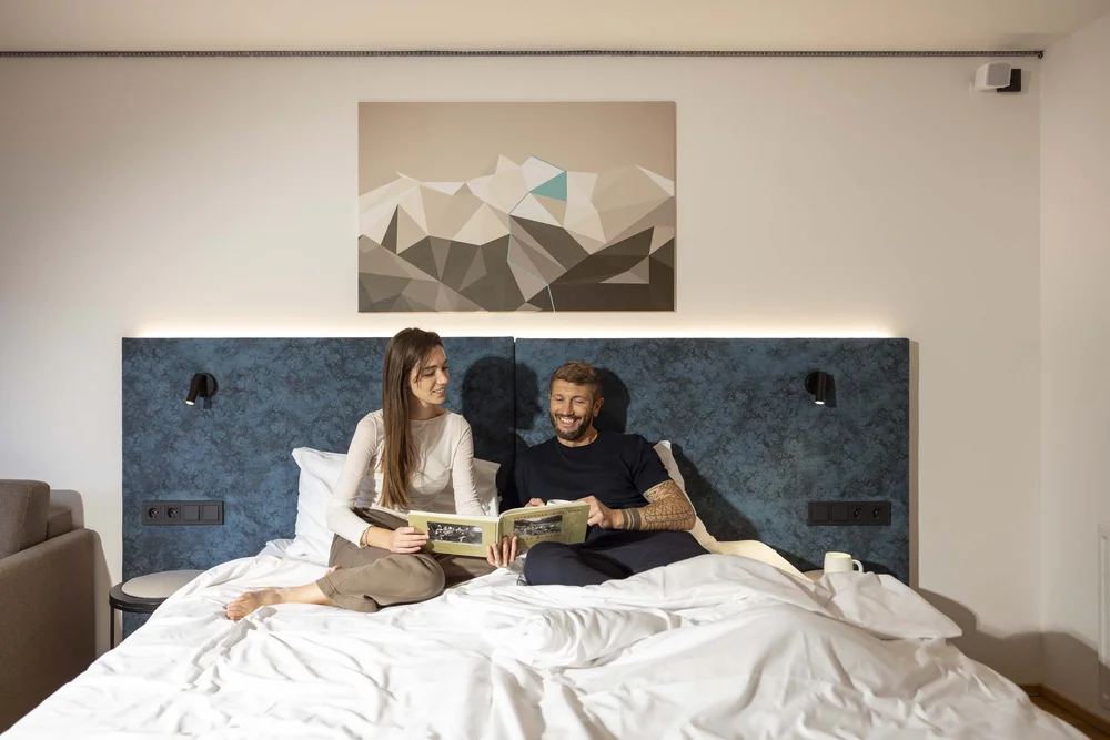 Coppia che legge un libro insieme a letto in una camera moderna